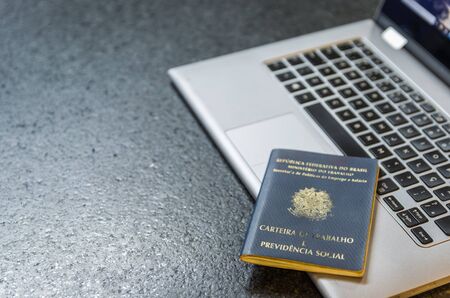 Translation: Federative Republic of Brazil, Ministry of Labor./ Brazilian Work Card (Carteira de Trabalho) and laptop computer.の写真素材