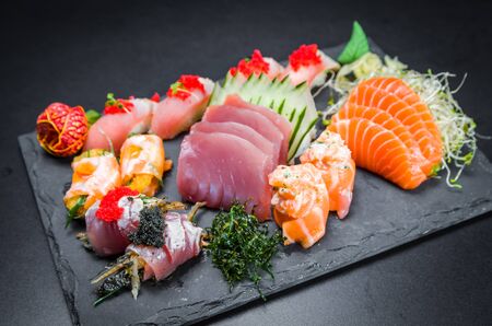 Sushi, traditional Japanese cuisine. Several delicious sushi on the decorated plate, black background. Group of sushi, Urakami, Nigori, Sushi jow, sashimi, tekamaki, etc ...の写真素材