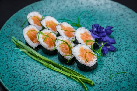 Perfect sushi, traditional Japanese cuisine. Delicious hossomaki on the decorated plate, black background.の写真素材