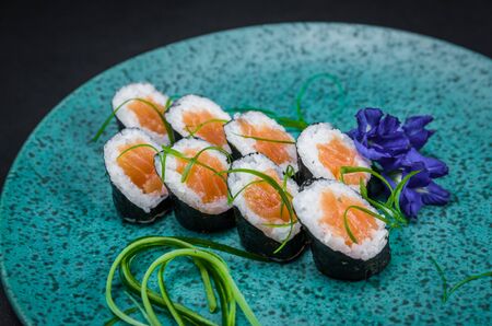 Perfect sushi, traditional Japanese cuisine. Delicious hossomaki on the decorated plate, black background.の写真素材