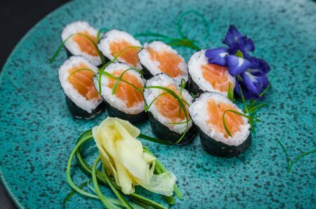 Perfect sushi, traditional Japanese cuisine. Delicious hossomaki on the decorated plate, black background.の写真素材