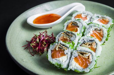 Perfect sushi, traditional Japanese cuisine. Delicious uramaki with sweet and sour sauce on the decorated plate, black background.の写真素材