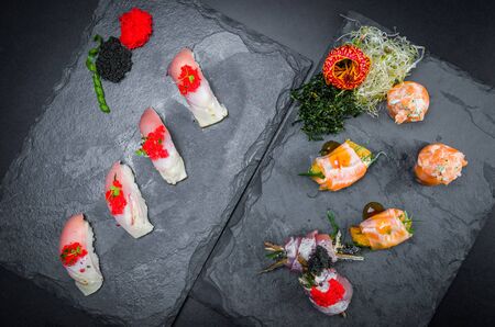 Sushi, traditional Japanese cuisine. Several delicious sushi on the decorated plate, black background. Group of sushi, Urakami, Nigori, Sushi jow, sashimi, tekamaki, etc ...の写真素材
