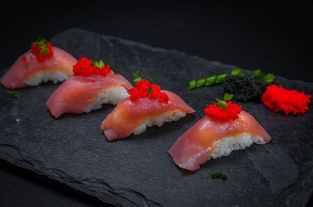 Perfect sushi, traditional Japanese cuisine. Delicious tuna kiguiri with capellin roe (caviar) on the decorated plate, black background.の写真素材