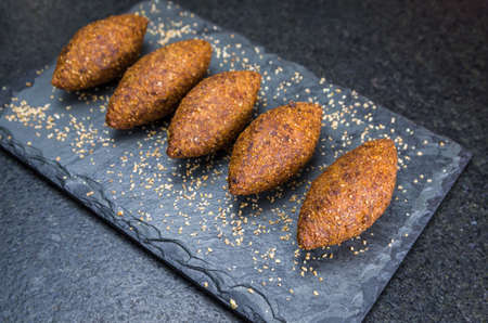Delicious Lebanese (Arabic) food, kibbeh (kibe) on black slate stone and granite background.の写真素材