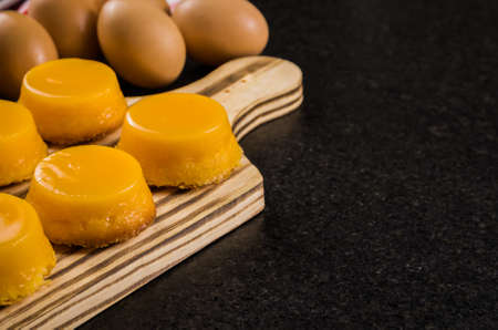Delicious Quindins on wooden board, traditional Brazilian dessert made with egg yolk, sugar and...