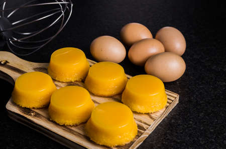 Delicious Quindins on wooden board, traditional Brazilian dessert made with egg yolk, sugar and...