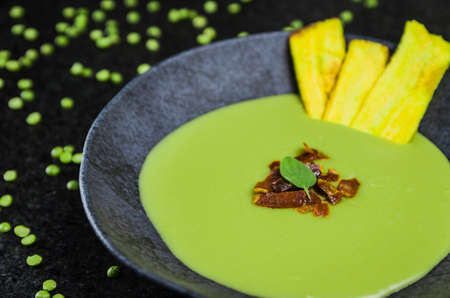 Delicious bacon pea cream with banana chips on a beautiful slate plate.の写真素材