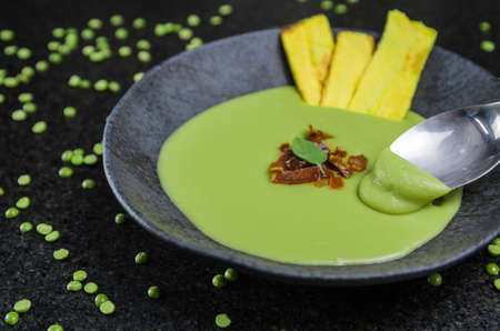 Delicious bacon pea cream with banana chips on a beautiful slate plate.の写真素材