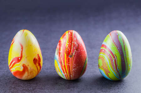 Colorful Easter eggs lined up side by side on a trendy black background.の写真素材