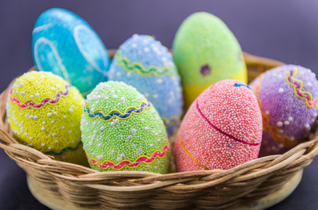Easter colored eggs in a basket isolated on a trendy black background. Minimal easter concept. Easter card with copy space for text.の写真素材