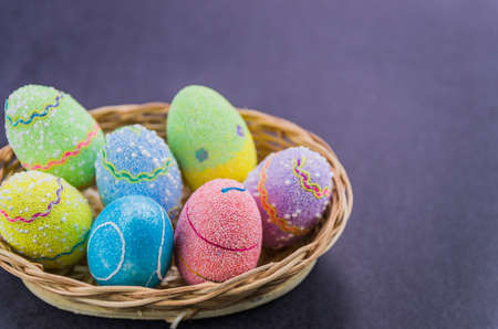 Easter colored eggs in a basket isolated on a trendy black background. Minimal easter concept. Easter card with copy space for text.の写真素材