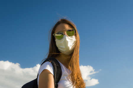 Girl wearing face protection mask looking at camera on sunny day