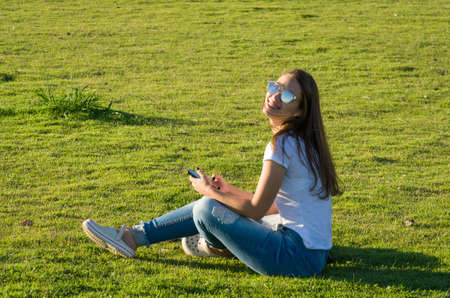 Young woman sitting on the grass with a protective mask during the SARS CoV-2 pandemic season , on the new Orla do Guaiba in Porto Alegreの写真素材