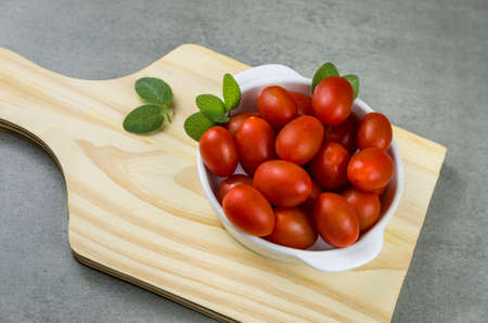 Wooden board with cherry tomatoes on gray background. culinary background.の写真素材