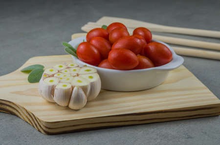 Wooden board with cherry tomatoes on gray background. culinary background.の写真素材
