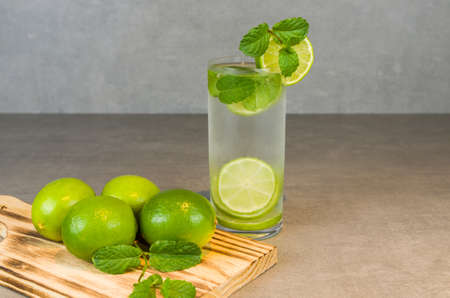 Mojito cocktail glass with mint and lime on a gray concrete background with fresh lime. Sparkling water and refreshing. place for textの写真素材