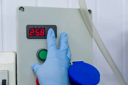 Woman working in industry, adjusting tank thermostat