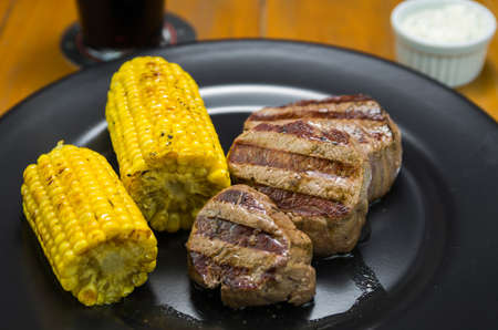 Delicious filet mignon close-up with roasted corn and glass of beer.の写真素材