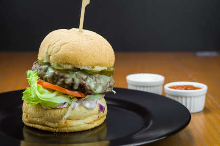 Close-up of tasty homemade hamburger on wooden table and black backgroundの写真素材