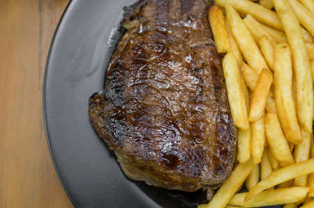 Delicious grilled entrecote dish with french fries and glass of beerの写真素材