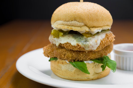 Close-up of homemade tasty chicken burger on wooden table and black background.の写真素材