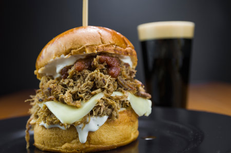 Close-up of tasty homemade pulled pork burger on wooden table and black backgroundの写真素材