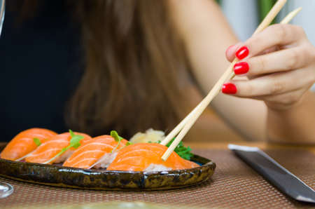 Woman eating delicious sushi, closeup on chopsticksの写真素材