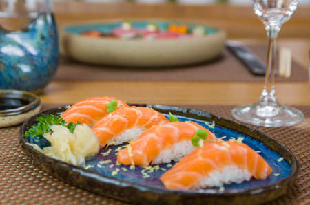 Delicious premium salmon nigiri on blue handmade plate decoratedの写真素材