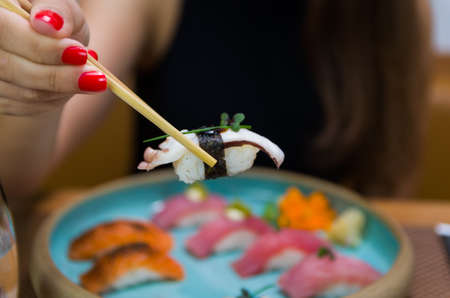 Woman eating delicious sushi, closeup on chopsticksの写真素材