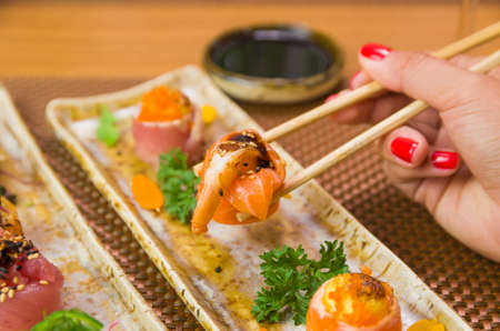 Woman eating delicious gunkan sushi, closeup on chopsticksの写真素材
