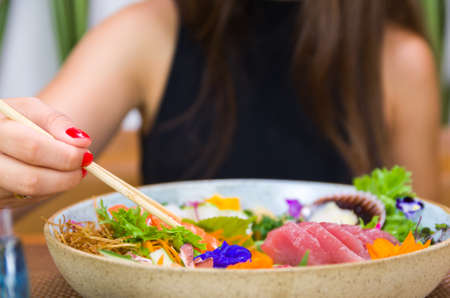 Woman eating delicious sushi, closeup on chopsticksの写真素材