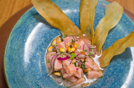 Delicious salmon ceviche with vegetables, spices and lemon close up on a plate on the table. horizontal top view from aboveの写真素材