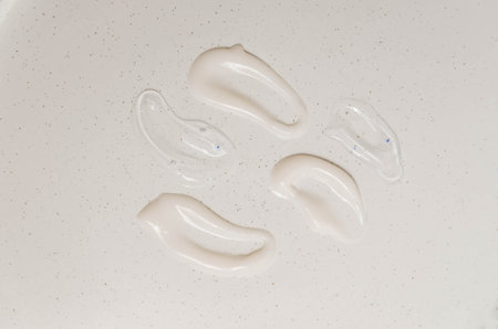Cosmetic smears of creamy texture on a beige background.