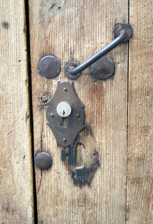 Detail of a weathered and aged door. A close up of the old fashioned locking mechanism, which has a modern lock added.  Picture taken in Cordoba, southern Spain.の写真素材