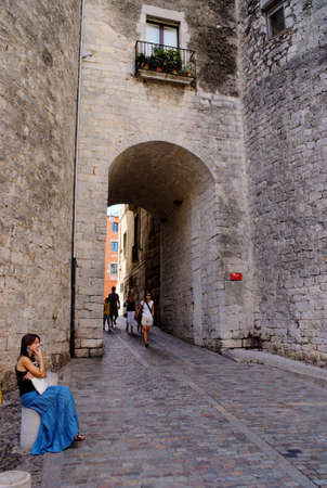 Girona / Spain / August 13 2010 : Heart of the beautiful historic old city. Medieval gate into the Jewish quarter near the magnificent cathedral. Holiday makers admire the view.のeditorial素材