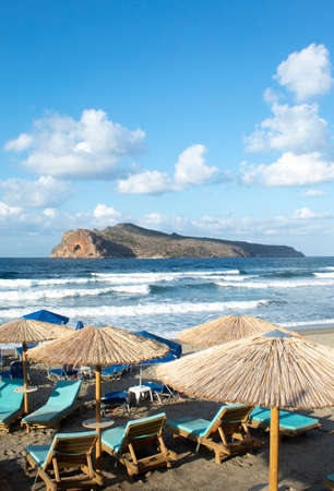 Crete island Greece Charming small resort of Agia Marina,  Chania Sun loungers and parasols on the beach View to Theodori island Portrait aspect with copy spaceの写真素材