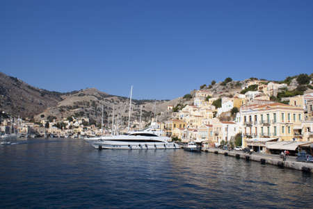 Symi island - Greece - August 19 2009 :  Beautiful harbor scene with bustling colorful waterfront.  Elegant houses line the busy harbor. Landscape aspect view.のeditorial素材