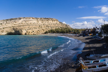Matala village on the south coast of the Greek island of Crete.  View of the beautiful beach towards the Roman caves. An archaeological site. Late afternoon with shadows as the sun goes down.の写真素材