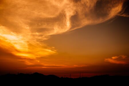 The skyline of the mountains and the oil production industry There is an orange-red light during the sunset. silhouette industrial.の写真素材
