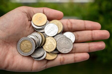 Clutch a coin to save money. The economy was bad during the epidemic. holding the coins on natural background. in saving money concept. copy spaceの写真素材