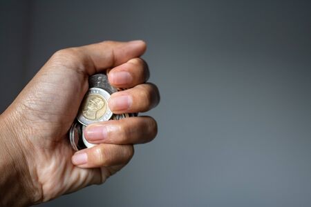 Clutch a coin to save money. The economy was bad during the epidemic. holding the coins  and the...