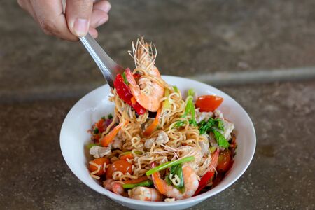Yum Instant Noodles Shrimp Fresh Thai style food of instant noodles salad with pork, herbs and celery on celery. Red tomatoes, white cups. Vintage. selective focus.の写真素材