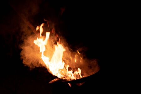 Red orange flame from the fire on the pan roasting cashews.fire,heat energy that ignites fuel at...