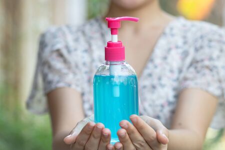 Woman hand holding hand gel, hand wash gel, hand pump with two hands. Alcohol, gel, antiseptic,...