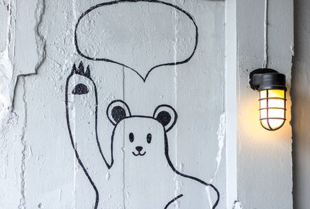Draw a cartoon teddy bear on the white wall. with speech bubble. And decorated with orange lanterns. copy space.の写真素材