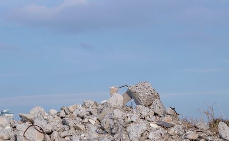 A large pile of sandy soil with a stone. Above, you can see blue sky and white clouds. Construction. A Pile Of Rocks with garbage.の写真素材