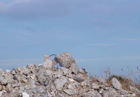 A large pile of sandy soil with a stone. Above, you can see blue sky and white clouds. Construction. A Pile Of Rocks with garbage.の写真素材