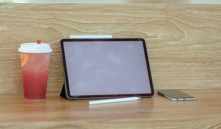 A tablet next to a Ice with sweet water topped with Fresh pink lemonade with raspberries decorated. candy summer. copy space.の写真素材