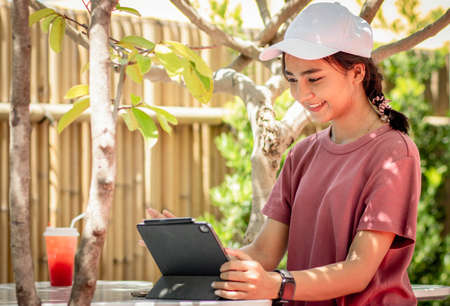woman working serious with a tablet computer at a wooden table. Next on the table is aIce with sweet water pink lemonade. concept man working from home using tablet computer. selective focus.の写真素材